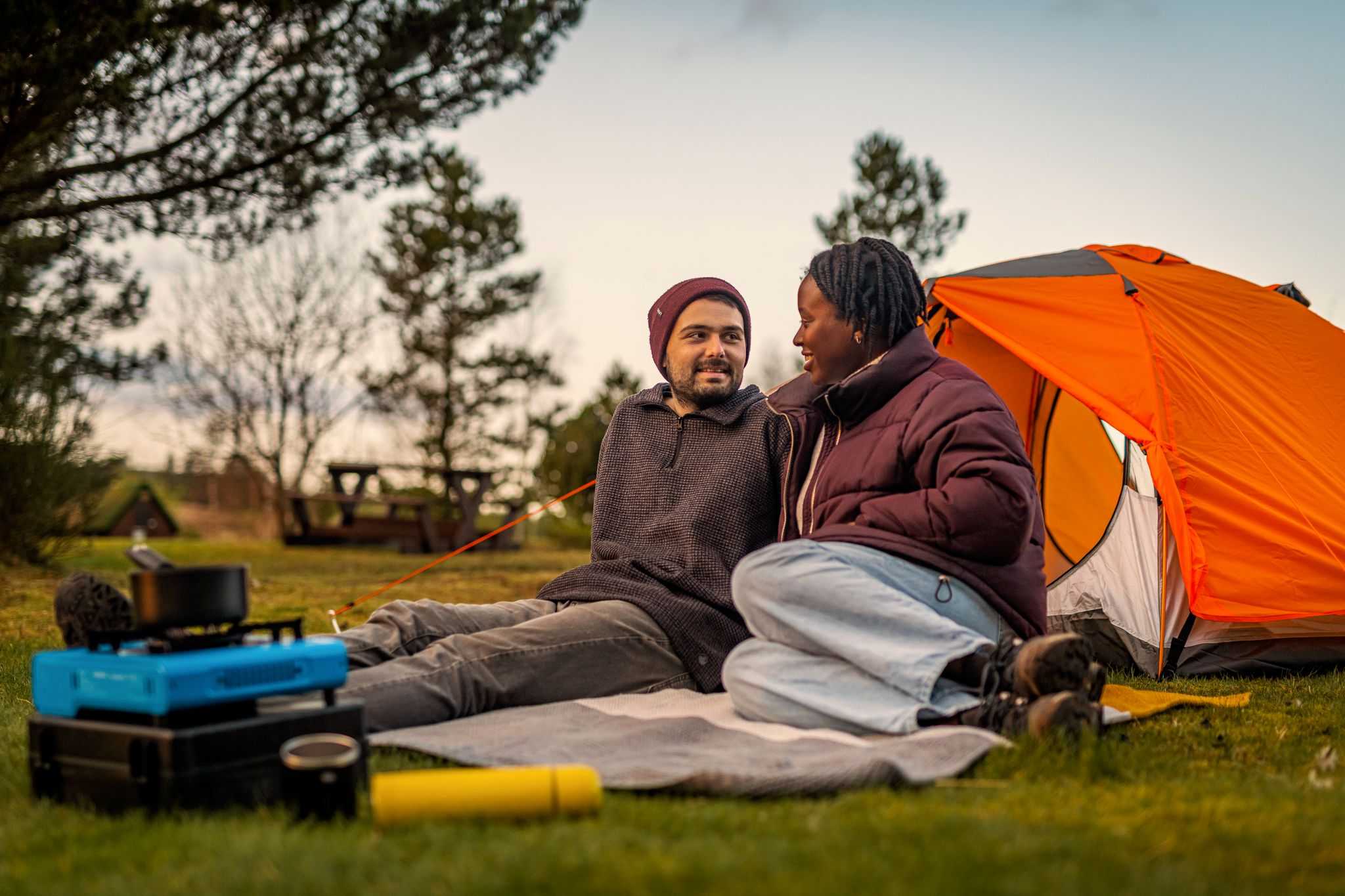 Man and woman sitting in front of orange tent