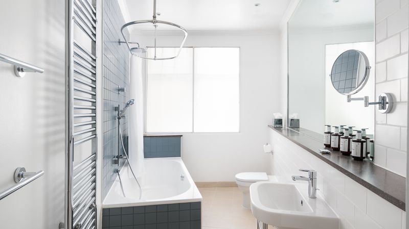 A clean and fresh looking white bathroom suite with complimentary products on a self by the mirror.